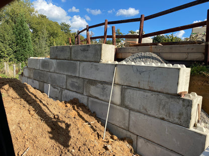Lange Stützmauer aus Beton Legosteinen entlang einer Baustelle