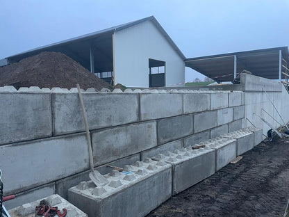 Mauer aus Beton Legosteinen vor einer Gewerbehalle
